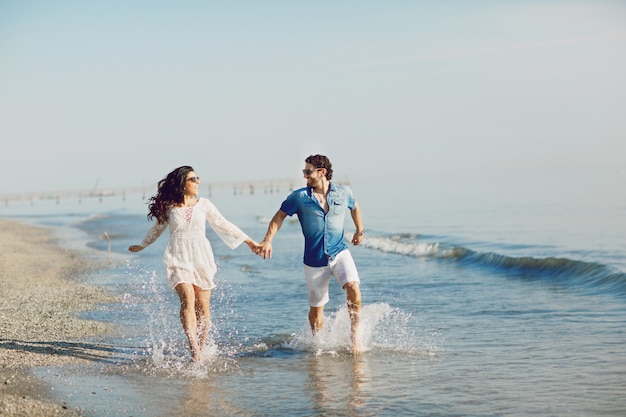 Happy couple walking and playing on the beach