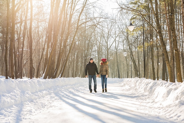 Happy couple walking through a snowy forest in winter.