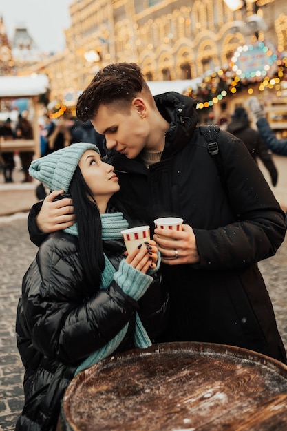 クリスマスマーケットでコーヒーを飲む暖かい服を着て幸せなカップル