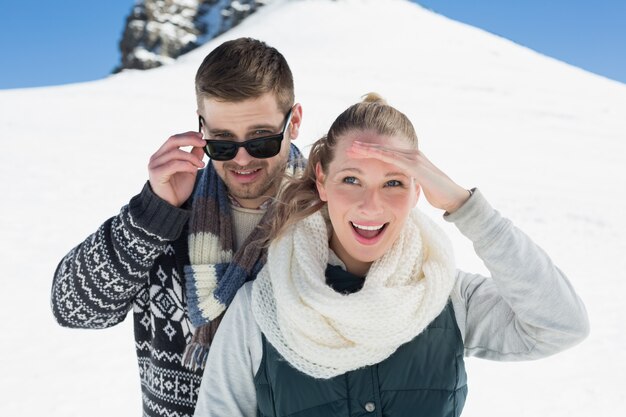 Happy couple in warm clothing in front of snowed hill