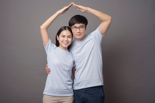 A happy couple wearing blue shirt is making armsroof in grey 