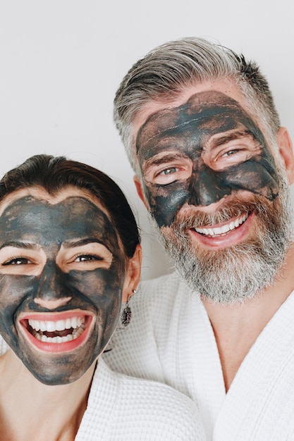 Happy couple wearing a charcoal mask