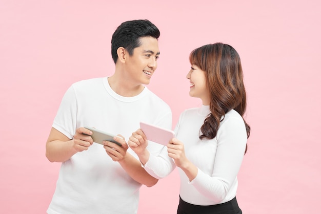 happy couple in white t-shirts with smartphones over pink background