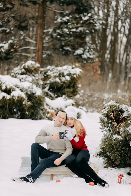 Happy couple in winter drinking tea and sitting on a sled