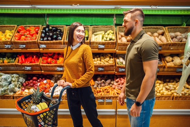 Happy couple with basket in grocery store together