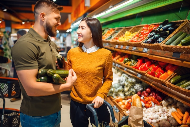 Happy couple with basket in grocery store