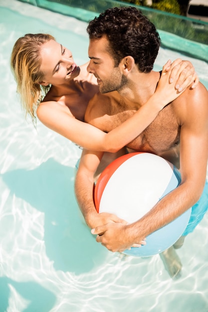 Счастливая пара с пляжным мячом в бассейне
