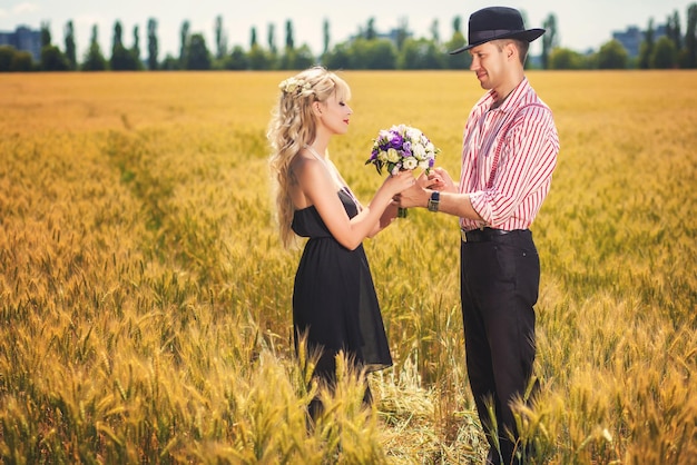 Happy couple with bouquet standing on wheat field