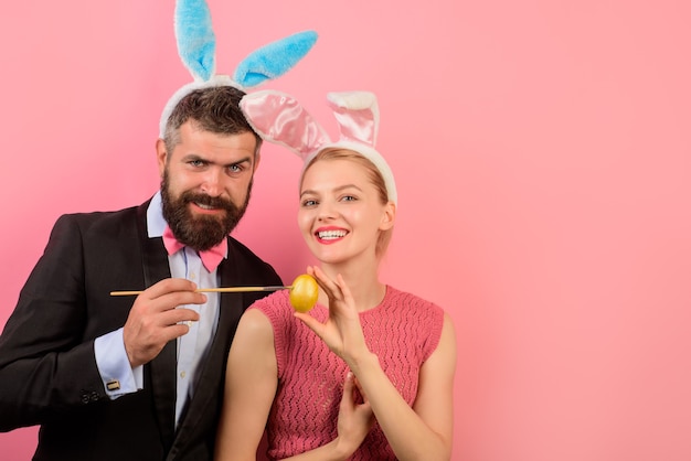 イースターのために卵を描くバニーの耳を持つ幸せなカップル。卵を飾る。家族はイースターを祝います。