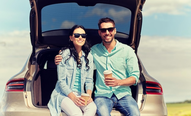 Photo happy couple with coffee at hatchback car trunk