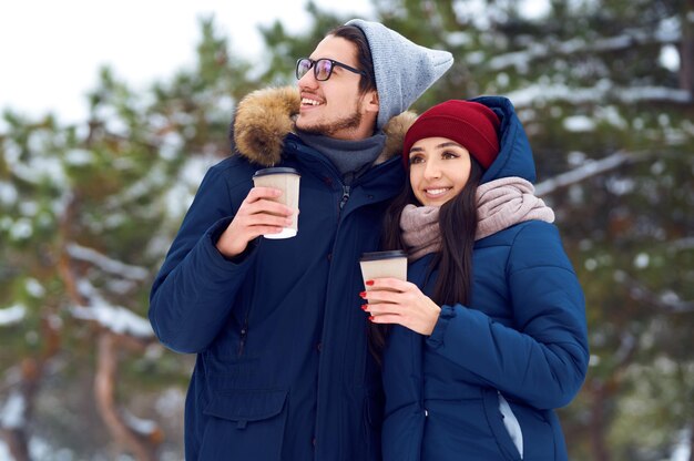 Happy couple with coffee in winter forest make selfie. . Happy winter time. Christmas.