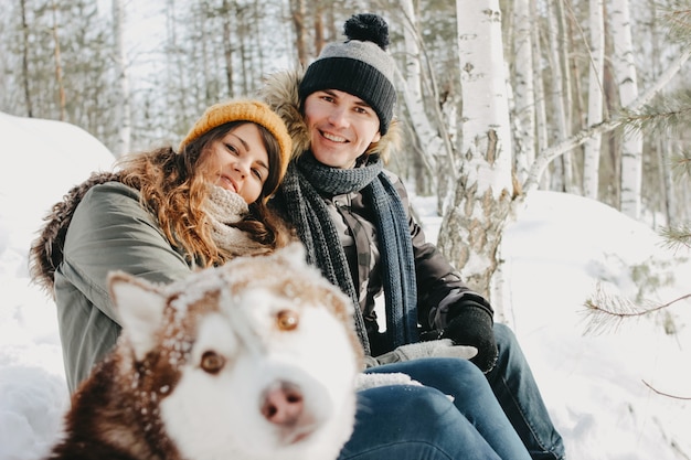 happy couple with dog haski at forest nature park in cold season.