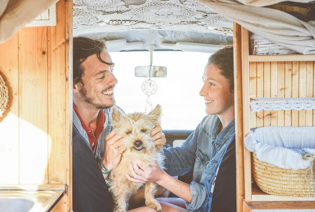 happy couple with dog sitting in caravan