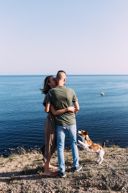 好きなペットの若い男性と女性との幸せなカップルは海の近くを歩いています