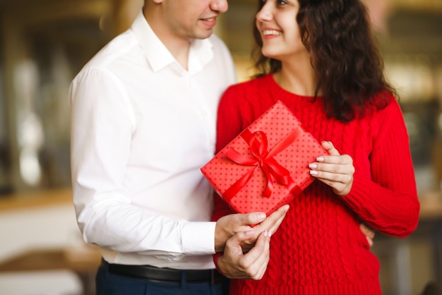 Photo happy couple with gift hugging red gift box in the hands of a couple in love valentine's day