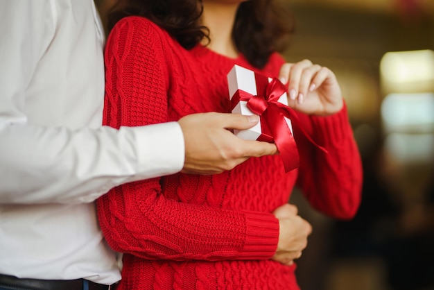 Happy couple with gift hugging Red gift box in the hands of a couple in love Valentine's Day