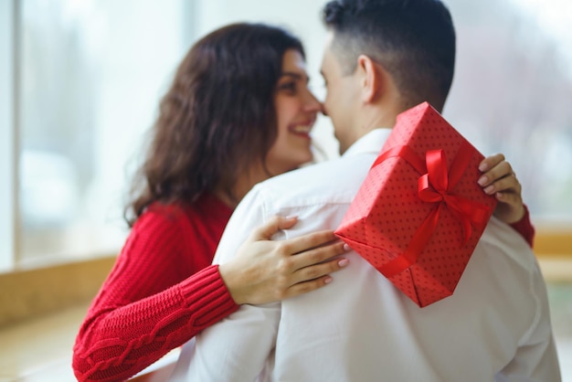 Happy couple with gift hugging Red gift box in the hands of a couple in love Valentine's Day