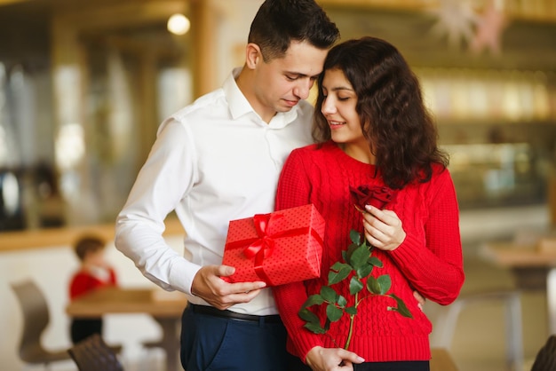 Happy couple with gift hugging Red gift box in the hands of a couple in love Valentines Day