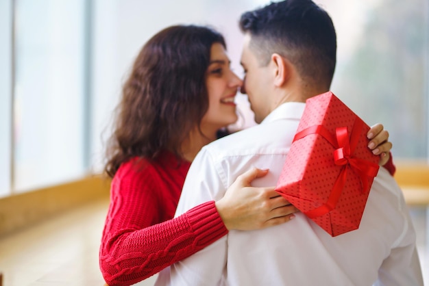 Coppia felice con abbracci regalo confezione regalo rossa nelle mani di una coppia innamorata il giorno di san valentino