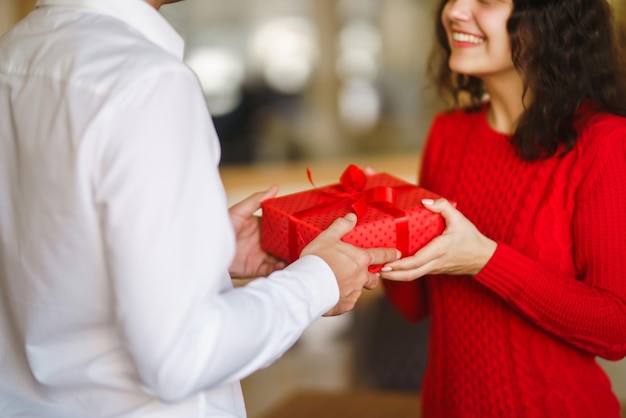 Foto coppia felice con abbracci regalo confezione regalo rossa nelle mani di una coppia innamorata san valentino