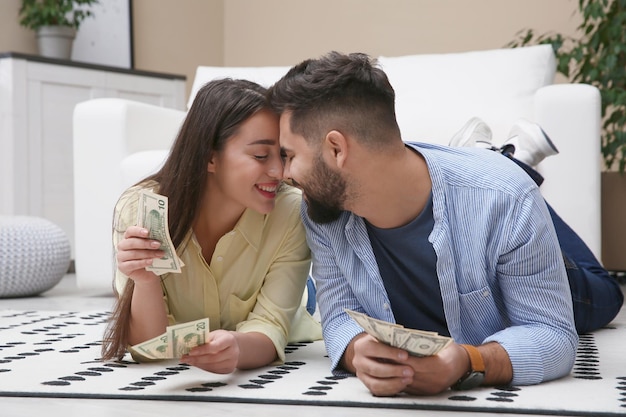 Photo happy couple with money on floor at home