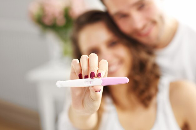Photo happy couple with pregnancy test in bedroom