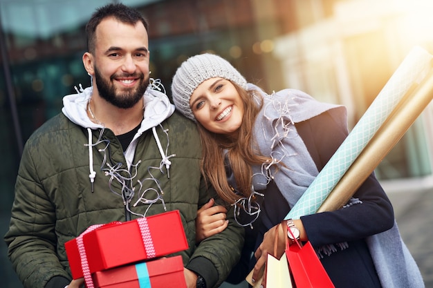 happy couple with shopping bags after shopping in city smiling and hugging