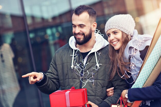 happy couple with shopping bags after shopping in city smiling and hugging