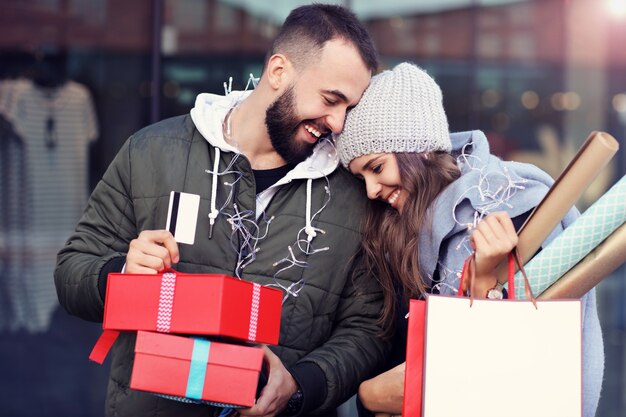 Coppia felice con le borse della spesa dopo lo shopping in città sorridendo e abbracciando