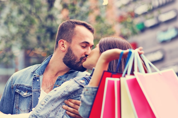 happy couple with shopping bags after shopping in city