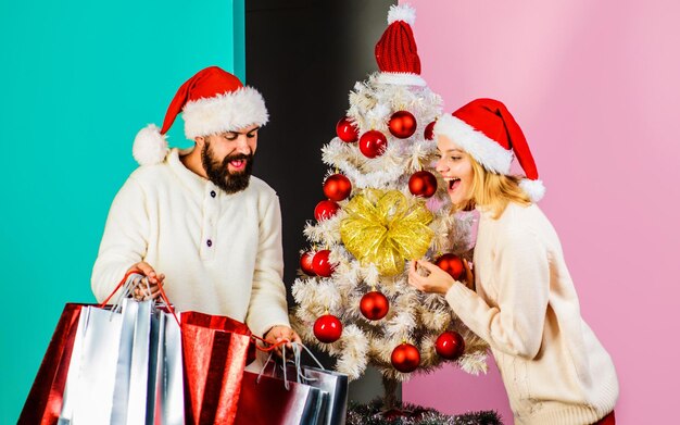 Happy couple with shopping bags buying christmas presents and gifts new year holiday season sale