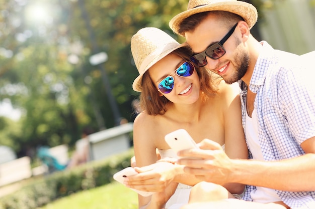 a happy couple with smartphones in the park