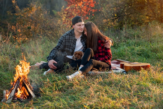 Happy couple with their funny dog sitting on the lawn in spring park.