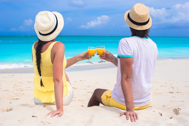 Happy couple with two glasses of orange juice on beach vacation