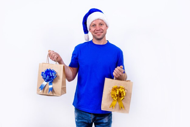 A happy courier in a blue uniform and Santa hat holds two gift bags