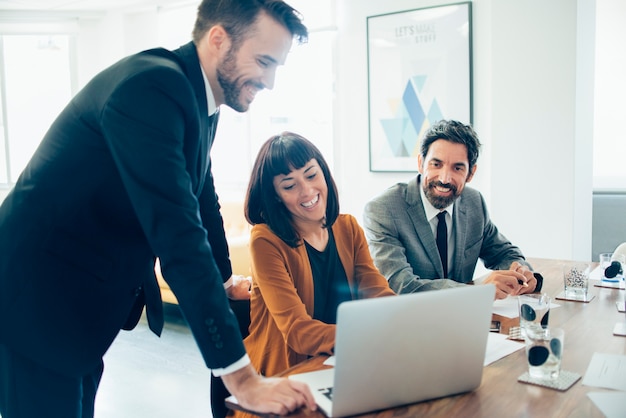 Happy coworkers laughing and using a laptop