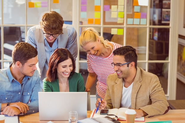 Happy creative business team using laptop in meeting