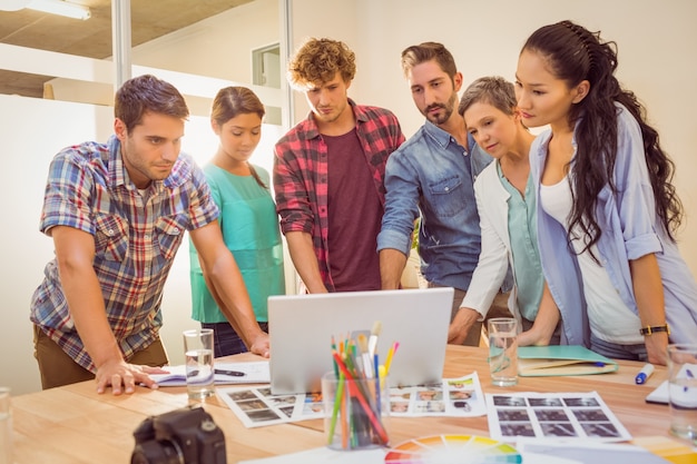 Happy creative business team using laptop in meeting