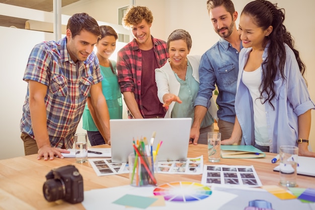 Happy creative business team using laptop in meeting