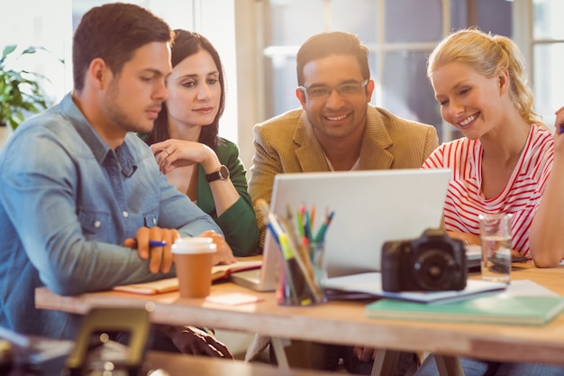 Happy creative business team using laptop in meeting