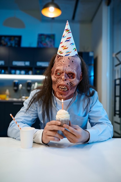 Happy creepy zombie employee with birthday cake portrait