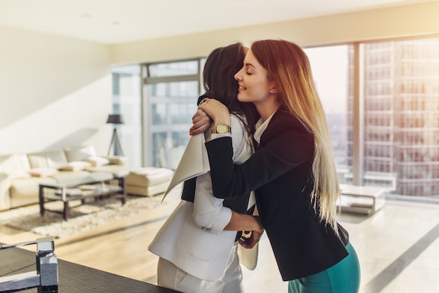 Happy customer hugging her real estate agent after successful deal.