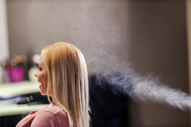 A happy customer is sitting in a hair salon with new hairstyle