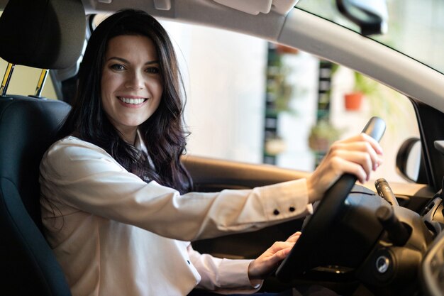 Donna felice del cliente che compra una nuova automobile nel centro di dealeship.