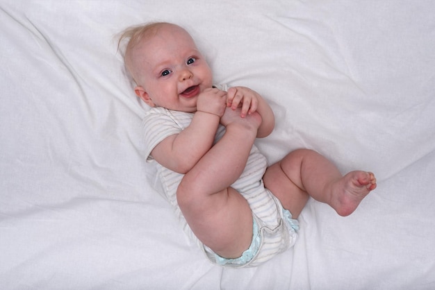 Happy cute 3 month baby girl with short blond hair lying on the white cloth nappy Newborn diapers