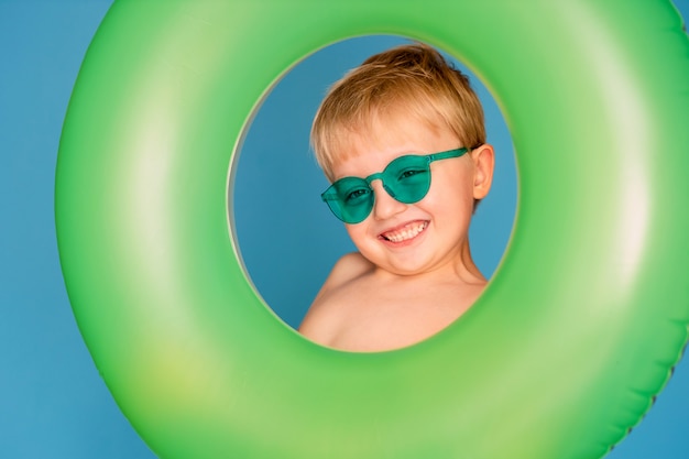 Happy cute baby boy 6-7 years old in sunglasses and with a life buoy.