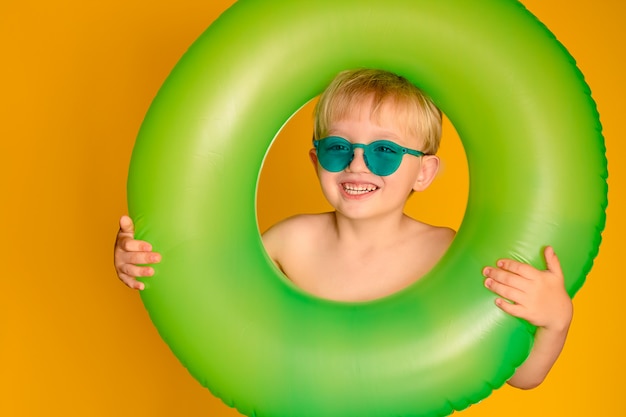 Happy cute baby boy 6-7 years old in sunglasses and with a life buoy. 