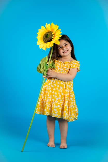 Happy cute baby girl fashionable yellow baby clothes posing studio on blue background