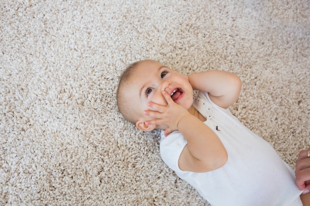 Happy cute baby lying on carpet