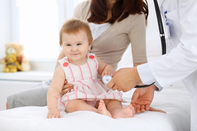 Photo happy cute baby with her mother at health exam at doctor's office